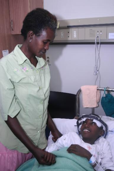 에티오피아 소년 아비 아사미뉴(오른쪽)가 1차 수술을 마친 뒤 서울 영동세브란스병원 병실에서 어머니 아사나쿠의 손을 꼭 잡은 채 활짝 웃고 있다. 굿네이버스 제공