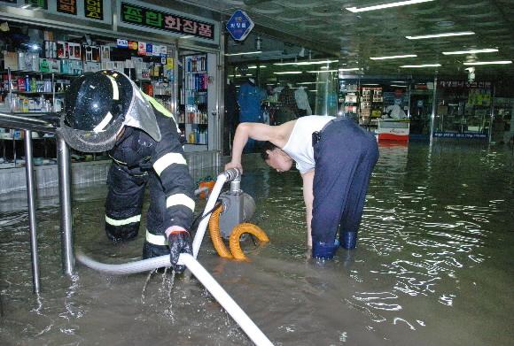 28일 오후 서울 중구 을지로 서울시청 신청사 공사현장에 고여 있던 물이 시청광장 지하쇼핑센터로 유입돼 일부 매장이 침수된 가운데 상인과 소방관들이 펌프를 이용해 물을 퍼내고 있다. 손형준기자 boltagoo@seoul.co.kr