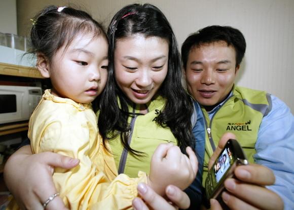 춘천에서 위탁부모와 함께 지내는 혜선양이 KTF 영상전화 서비스 ‘쇼 천사’를 이용해 강릉에서 일하는 아빠의 모습을 보고 있다. KTF 제공