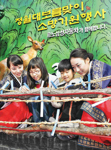 르노삼성차가 올 3월 개최한 ‘정월 대보름맞이 소망기원’ 행사에서 참가자들이 소원을 적은 쪽지를 새끼줄에 매달고 있다. 르노삼성차 제공