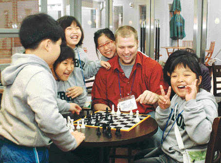 KB국민은행 영어캠프에 참여한 어린이들이 외국인 강사와 함께 체스를 두며 즐거워하고 있다. 국민은행 제공