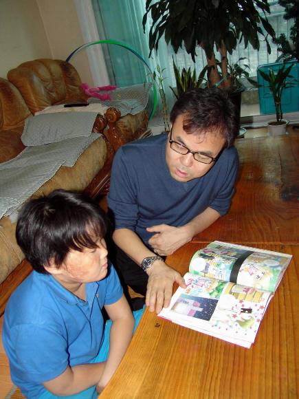 화재로 온 몸에 화상을 입고 심한 정신적 후유증까지 겪은 이상용(왼쪽)군이 아버지 이근우씨와 2일 책을 읽고 있다.