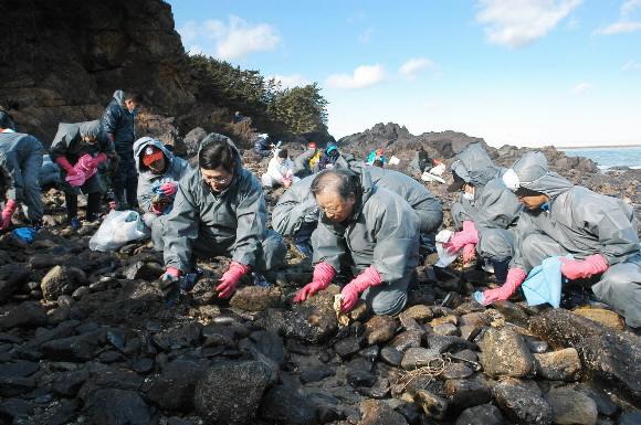 조석래(오른쪽에서 세번째) 전국경제인연합회장이 임직원들과 함께 2일 시무식을 겸해 충남 태안군 소원면 모항항에서 바위에 묻은 기름때를 닦고 있다. 전경련 제공