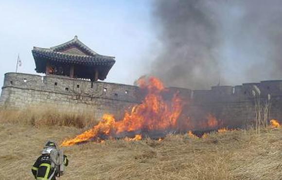 지난 15일 경기 수원 화성(華城) 앞 억새밭에서 소방 호스를 멘 소방관이 화재 지점으로 접근하고 있다. 수원중부소방서 제공