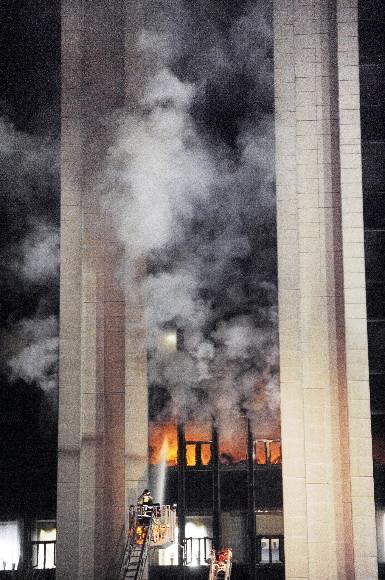 21일 0시35분쯤 서울 세종로 정부중앙청사 5층에서 발생한 불이 사무실 집기와 서류 등을 태운 뒤 연기가 건물 전체로 번지는 가운데 한 소방관이 사다리차에 올라 화재를 진압하고 있다. 김명국기자 daunso@seoul.co.kr