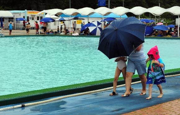 텅빈 수영장  기상청의 주말 예보가 4주째 빗나간 가운데 20일 서울 여의도 한강고수부지 수영장을 찾은 한 가족이 천둥을 동반한 비가 내리자 수영을 포기한 채 비를 피하고 있다. 도준석기자 pado@seoul.co.kr