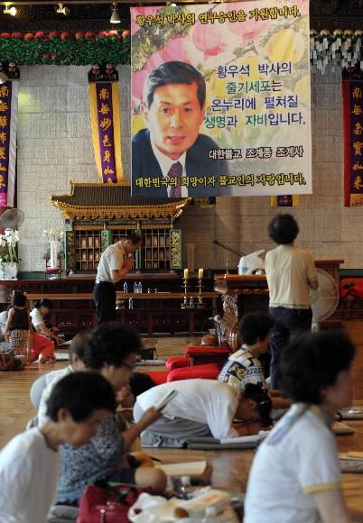 30일 황우석 박사의 연구 승인 기원 내용을 담은 플래카드가 걸린 조계사 대웅전에서 신도들이 예불을 하고 있다. 정연호기자 tpgod@seoul.co.kr