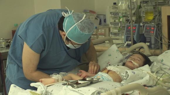 흉부외과는 과도한 업무로 ‘의학계의 3D’로 통한다.한 흉부외과 의사가 어린이 환자를 돌보고 있다.