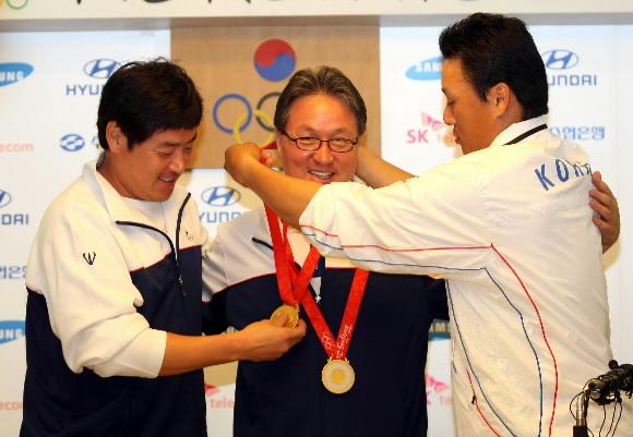 한국야구를 올림픽 정상으로 이끌었지만 23일 정작 시상대에 오르지 못한 김경문(가운데) 감독에게 진갑용(왼쪽)과 이승엽이 자신들이 받은 금메달을 걸어주고 있다. 올림픽에서 감독들에겐 메달이 주어지지 않는다. 베이징 올림픽사진공동취재단