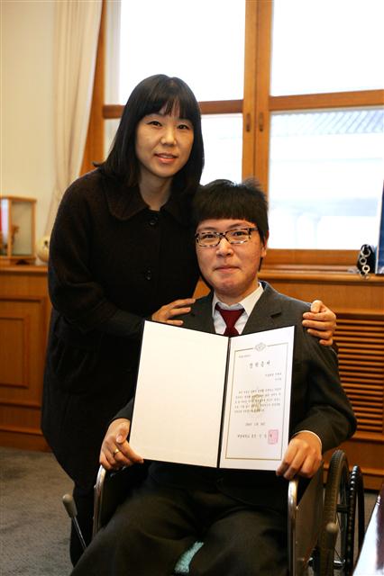 백경화씨가 아들인 시원군과 함께 계명대로부터 받은 특별장학증서를 펼쳐보이면서 포즈를 취하고 있다. 계명대 제공