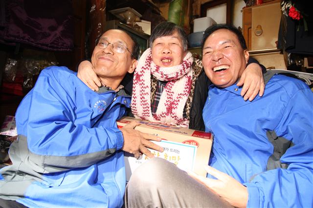 이윤우(오른쪽) 삼성전자 부회장과 한용외(왼쪽) 삼성사회봉사단장이 17일 서울 종로구 창신동 쪽방을 찾아 혼자 살고 있는 노인에게 쌀과 라면,삼성전자 여직원들이 직접 짠 목도리를 전달한 뒤 환하게 웃고 있다. 삼성 제공