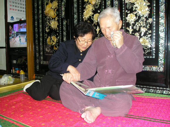 23일 실향민 이춘재씨가 아내 홍명순씨와 함께 북에 두고 온 가족들의 옛 사진을 보며 눈물을 훔치고 있다. 