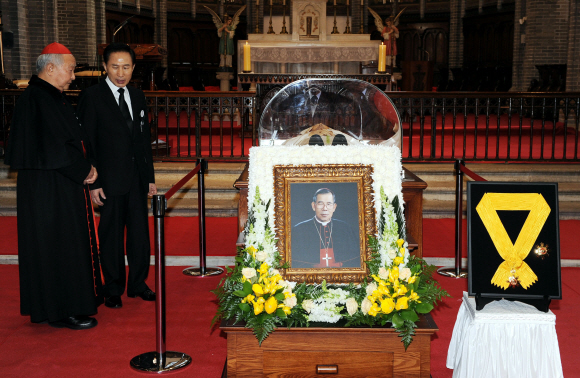 이명박(오른쪽) 대통령이 17일 서울 명동성당 대성당에 마련된 김수환 추기경의 빈소를 찾아 조문한 뒤 장례위원장인 정진석 추기경을 위로하고 있다. 오른쪽에 보이는 국민훈장 무궁화장은 김 추기경이 유신 선포 이전인 1970년 받은 것을 정부가 다시 제작해 갖다 놓은 것이라고 장례위원회가 밝혔다.  최해국기자 seaworld@seoul.co.kr 