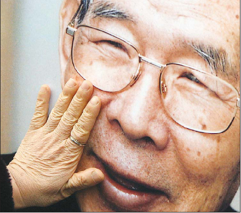 19일 오후 한 조문객이 명동성당 입구에서 인자하게 웃는 모습을 담은 김수환 추기경의 사진을 어루만지고 있다. 