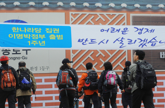 이명박 대통령 취임 1주년(25일)을 사흘 앞둔 22일 경제살리기 의지를 보여주는 문구를 담은 플래카드가 걸린 서울 종로구의 거리를 시민들이 걸어가고 있다. 이언탁기자 utl@seoul.co.kr