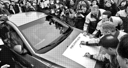 GM대우 관계자들이 24일 전북 군산항 자동차 전용부두에서 첫 수출길에 오르는 라세티 프리미어 수출 1호 차량에 성공을 기원하는 서명을 하고 있다. GM대우 제공