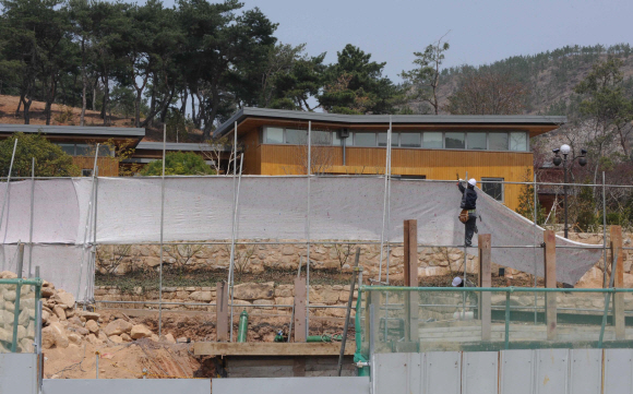 88일 경남 김해시 봉하마을 노무현 전 대통령의 사저 주위에서 공사 관계자들이 가림막을 설치하고 있다. 가림막은 사저 앞에 있는 노 전 대통령의 생가 복원 공사장에서 발생한 먼지가 날아 드는 것을 막기 위한 것이다. 김해 안주영기자 jya@seoul.co.kr