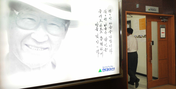 현대아산 근로자 억류 등 개성공단 문제가 꼬여만 가고 있는 상황에서 22일 현대아산 계동 본사에서 직원이 대북 경제교류의 물꼬를 튼 고(故) 정주영 명예회장의 사진 옆을 지나가고 있다.  안주영기자 jya@seoul.co.kr 