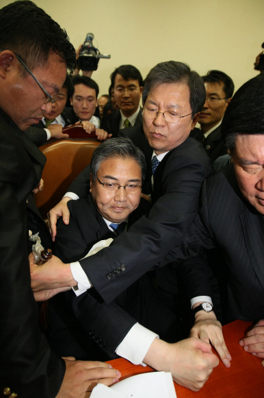 22일 오전 국회 외교통상통일위원회 박진(가운데 앉은이) 위원장이 야당 의원들에게 의사봉을 빼앗기자 주먹을 이용해 한·미 자유무역협정(FTA) 비준동의안을 가결시키고 있다. 김명국기자 daunso@seoul.co.kr 