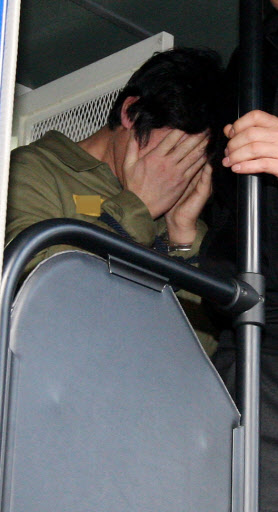 22일 연쇄살인범 강호순이 선고 공판에 앞서 얼굴을 감싼 채 호송차에서 내리고 있다.  연합뉴스