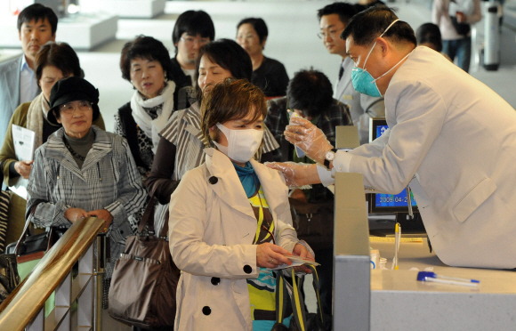 국내에서 첫 돼지인플루엔자 추정 환자가 발생한 가운데 28일 인천국제공항 입국장에서 공항검역소 직원이 한 일본인 관광객을 대상으로 체온검사를 하고 있다. 손형준기자 boltagoo@seoul.co.kr