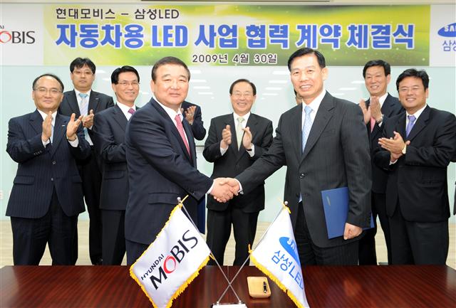 현대모비스 정석수(왼쪽) 사장과 삼성LED 김재욱 사장이 자동차 헤드램프용 LED 및 모듈에 관한 기술협력 계약을 체결한 뒤 악수하고 있다. 현대모비스 제공