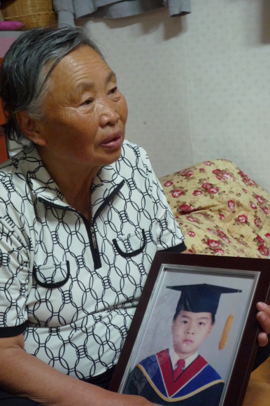며느리가 버린 두 손자를 키워낸 이연희 할머니가 손자 이모(18)군의 유치원 졸업사진을 들고 있다.