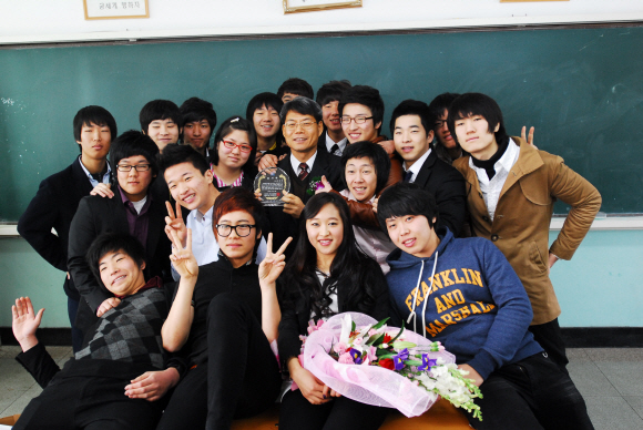 윤정현(가운데 기념패 든 사람) 교사가 지난해 스승의 날을 맞아 학교로 찾아온 제자들과 사제지간의 정을 나누며 환하게 웃고 있다. 보성실업고 제공 