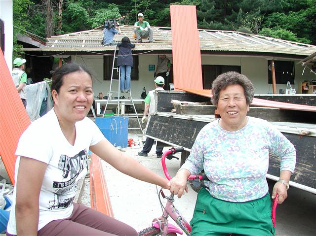 15일 강원 춘천시 서면 덕두원마을 조순희(오른쪽) 할머니와 필리핀 출신 며느리 마릴료우가 농협 봉사단들의 집수리 봉사활동에 기뻐하고 있다.