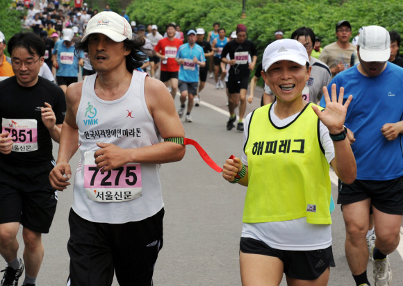 시각장애인들이 해피레그 자원봉사자 김기욱씨의 도움을 받으면서 뛰고 있다.