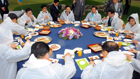 &#57544;이명박(가운데) 대통령이 22일 청와대 녹지원에서 중소기업인들과 만찬을 하며 건의사항을 듣고 있다. 비가 내리자 이 대통령을 비롯한 참석자들은 비옷을 입고 야외에서 만찬을 했다. 　최해국기자 seaworld@seoul.co.kr&#57543; 　