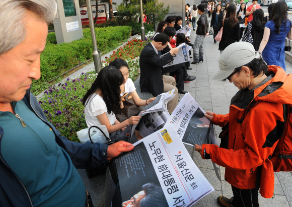 서울신문 호외 읽는 시민들  23일 오후 서울시청 근처를 지나던 시민들이 노무현 전 대통령의 서거 소식을 담은 본지 호외를 비통한 표정으로 읽고 있다.  류재림기자 jawoolim@seoul.co.kr 