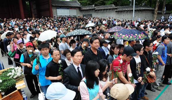 노무현 전 대통령 서거 이튿날인 24일 서울 덕수궁 대한문 앞에 마련된 임시 분향소를 찾은 수많은 추모객들이 국화꽃을 들고 분향 순서를 기다리고 있다. 손형준기자 boltagoo@seoul.co.kr