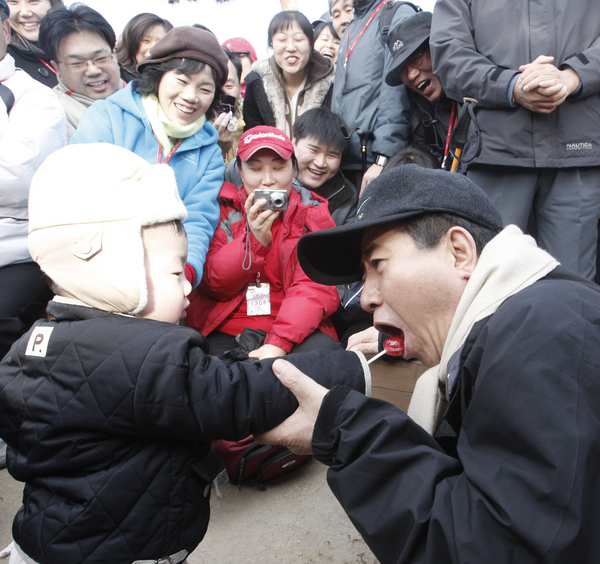 노무현 전 대통령이 2008년 1월 13일 노사모 산행에 참가해 아이의 사탕을 두고 장난을 치고 있다.