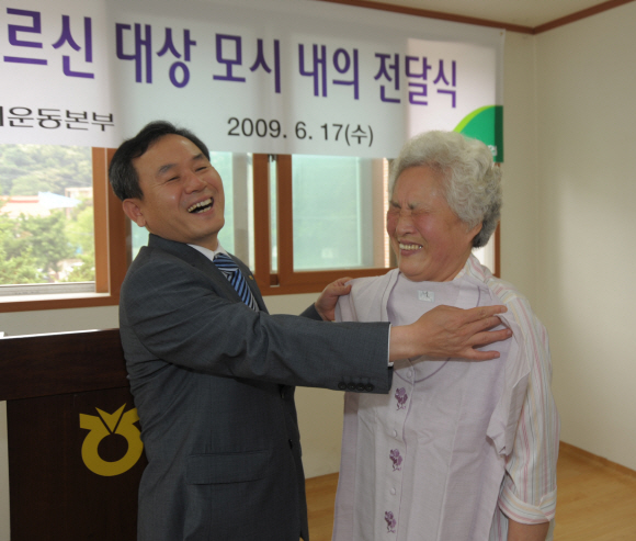 지난 17일 경기 광주시 중대동 텃골마을회관에서 정영자(오른쪽) 할머니가 신충식 농협 상무와 모시내의의 크기를 맞춰보며 파안대소하고 있다. 농협 제공