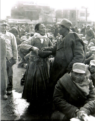 “아들아…”  신병인 아들을 재회의 기약이 없는 전선으로 떠나보내는 어머니가 애처로운 표정으로 한 바가지의 물을 건네고 있다. 1950년 12월19일 대구역 앞의 모습이다.