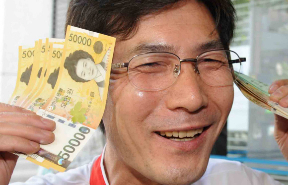 한 시민이 23일 서울 중구 남대문로 한국은행 본점에서 새 5만원권을 교환한 뒤 신권을 흔들며 즐거워하고 있다. 안주영기자 jya@seoul.co.kr