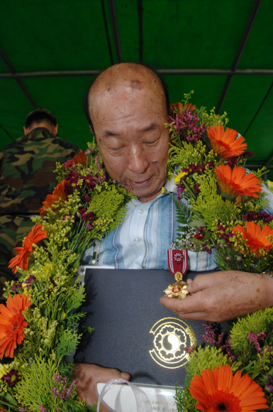 최영학씨가 25일 이상의 3군사령관으로부터 전달받은 화랑무공훈장을 어루만지고 있다.  육군 제공