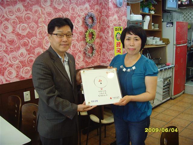 충북공동모금회 박용훈(왼쪽) 부장이 청주시 흥덕구 가경동 명동김밥 주인 김순임씨에게 ‘착한가게 27호점’ 현판을 전달하고 있다.  충북공동모금회 제공 