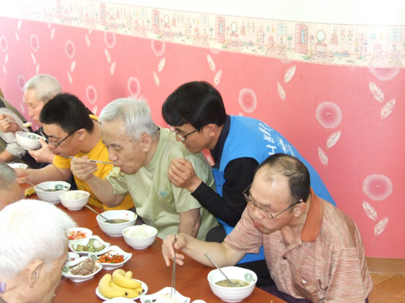 인천 두산인프라코어 봉사단 정광수(오른쪽에서 두번째)씨가 인천 부평동 즐거운집을 찾아 장애인들에게 식사를 대접하고 있다. 