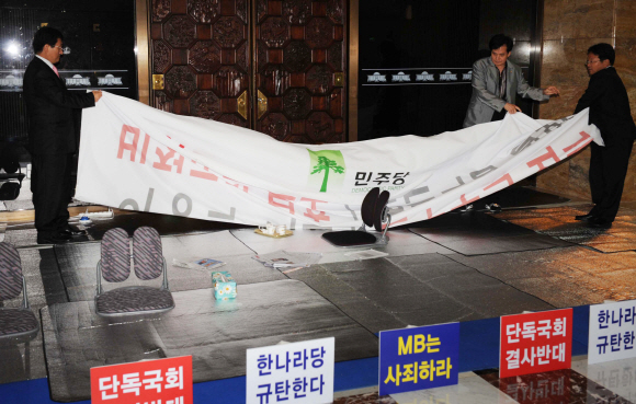 2일 오후 민주당 지도부가 국회 등원을 결정한 직후 강기정(오른쪽) 의원 등 민주당 관계자들이 국회 중앙홀(로텐더홀) 앞에 내걸었던 현수막을 정리하고 있다. 이언탁기자 utl@seoul.co.kr