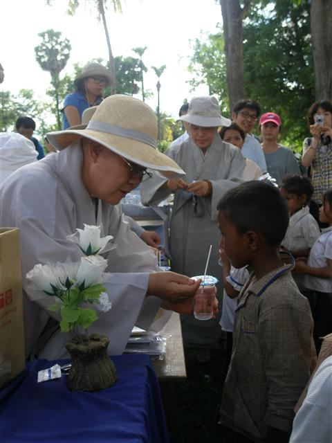 지난 7일(현지시간) 캄보디아 시엠리아프 꼭부초등학교에서 열린 구호행사에서 비구니 스님이 현지 어린이에게 구충제를 먹이고 있다.