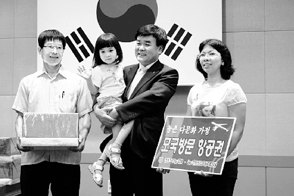 김종운(가운데) 농협전북본부장이 지난 14일 다문화가정 모국방문 지원 행사에서 항공티켓을 받은 태국 출신 결혼이주여성 아농잔타노(오른쪽)씨의 딸을 안고 포즈를 취하고 있다. 농협중앙회 제공