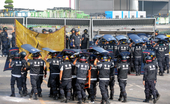 경찰과 노조의 팽팽한 대치가 나흘째 이어지고 있는 쌍용차 경기 평택공장에서 23일 경찰이 방패로 머리를 가린 채 임무를 교대하고 있다. 도준석기자 pado@seoul.co.kr