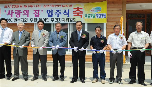 충북 청원군 북이면 장석연씨의 러브하우스 입주식에서 도움을 준 청원군과 사회단체 관계자들이 테이프커팅을 하고 있다. 청원군 제공