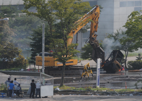 4일 쌍용자동차 평택공장에서 경찰의 진입작전이 개시된 가운데 사측 직원들이 중장비를 동원해 불에 탄 지게차와 바리케이드를 치우고 있다. 정연호기자 tpgod@seoul.co.kr