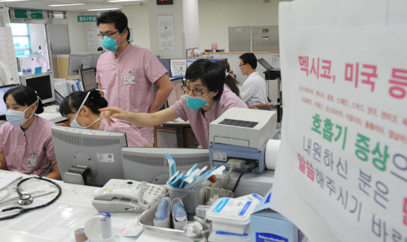 마스크 업무  신종플루 감염자가 3000명을 돌파하는 등 급속히 확산되고 있는 가운데 24일 서울 강북삼성병원 응급실에서 의사와 간호사들이 마스크를 착용한 채 업무를 보고 있다. 이언탁기자 utl@seoul.co.kr