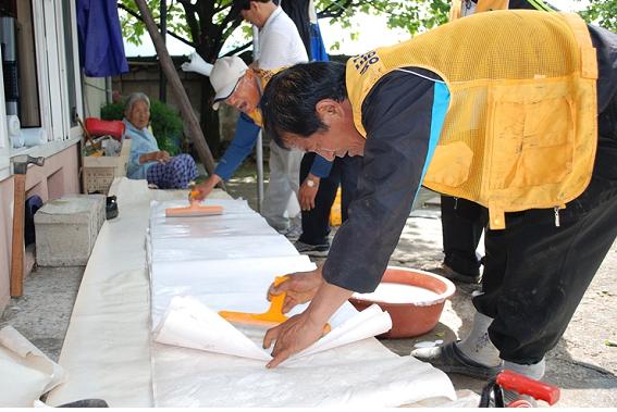충북 영동군 감나무봉사단이 불우 이웃들을 위해 도배를 해 주고 있다. 2001년에 구성된 봉사단은 9년째 다양한 봉사활동을 하고 있다.  영동군자원봉사센터 제공