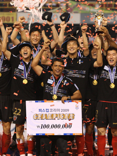 16일 포항 스틸야드 경기장에서 열린 피스컵 코리아 결승전에서 부산을 꺾고 우승한 포항의 파리아스(피켓 든 이) 감독과 선수들이 목에 우승 메달을 건 채 환호하고 있다.  포항 연합뉴스