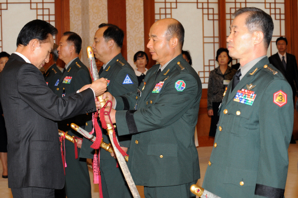 이명박(왼쪽) 대통령이 17일 청와대에서 대장진급 및 보직신고를 받고 정승조 1군사령관의 삼정도에 수치를 달아주고 있다. 오른쪽은 김상기 3군사령관. 최해국기자 seaworld@seoul.co.kr